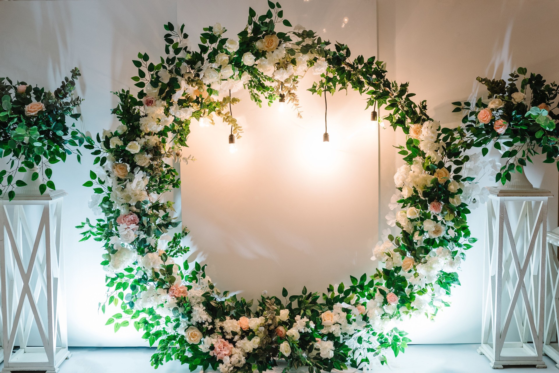 Arch decorated with a composition of white, pink flowers and greenery in the banquet hall. Decor in the banquet area at the wedding party.